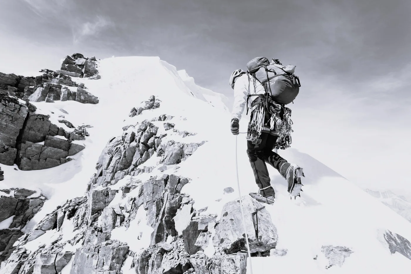 A single climber stepping onto an exposed summit ridge